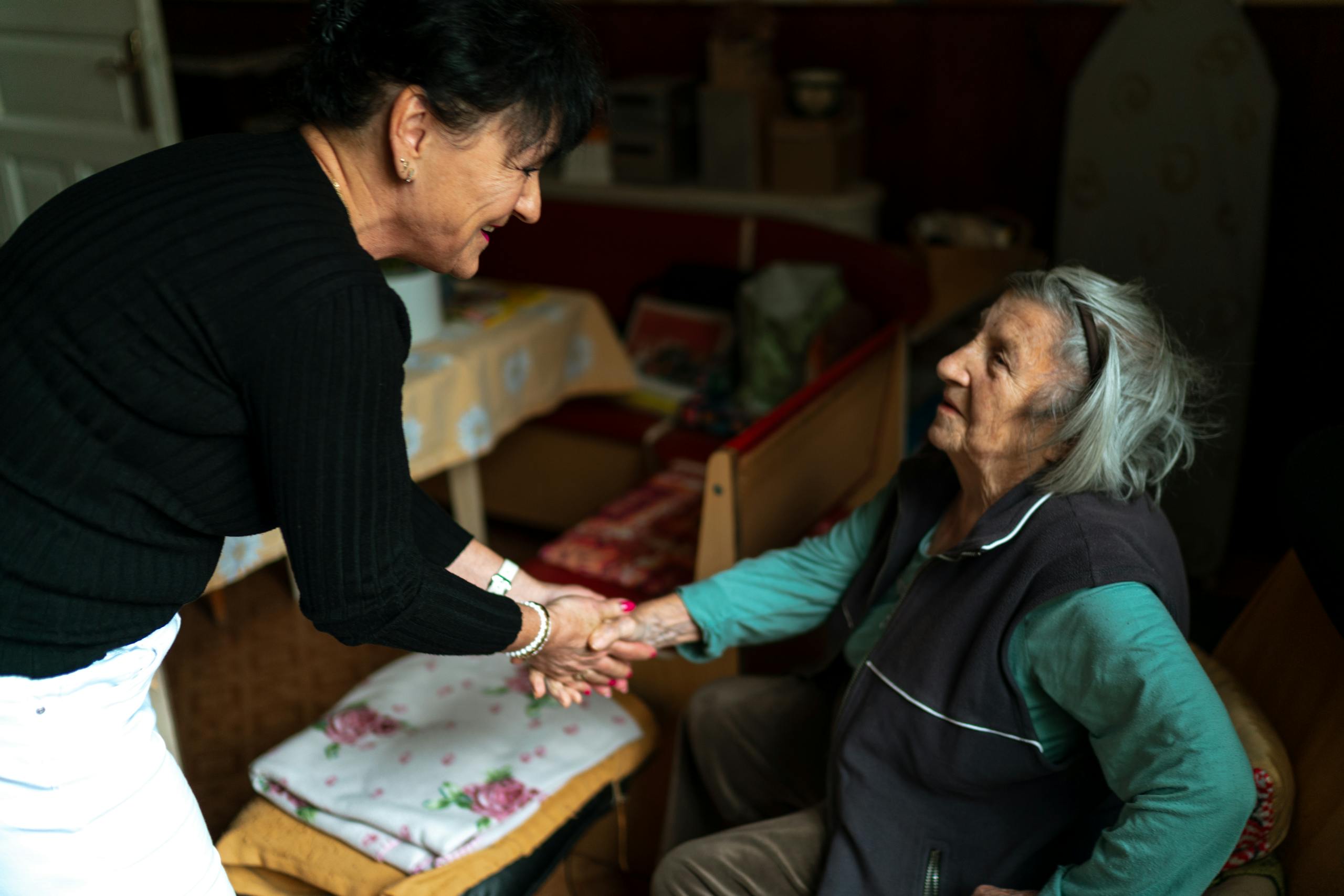 A caregiver gently holding the hand of an elderly person with dementia