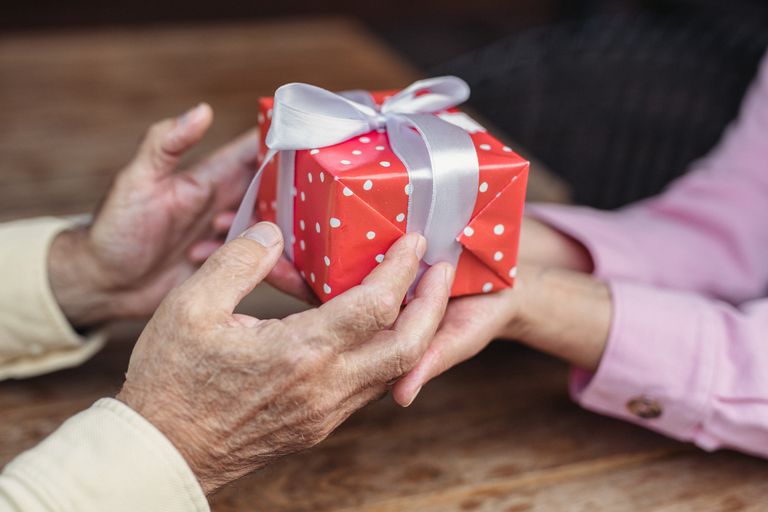 A family member giving a thoughtful gift to an elderly person with dementia